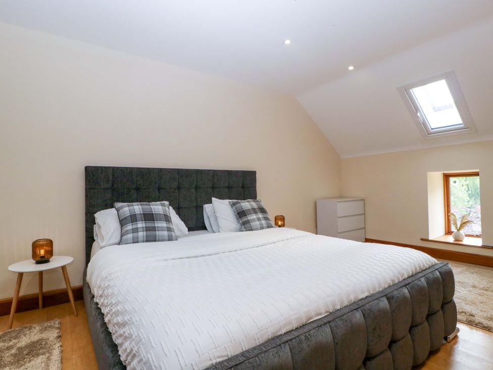 A bedroom with a bed, nightstand, and window at Heathcliffe House, Castleton near Cardiff