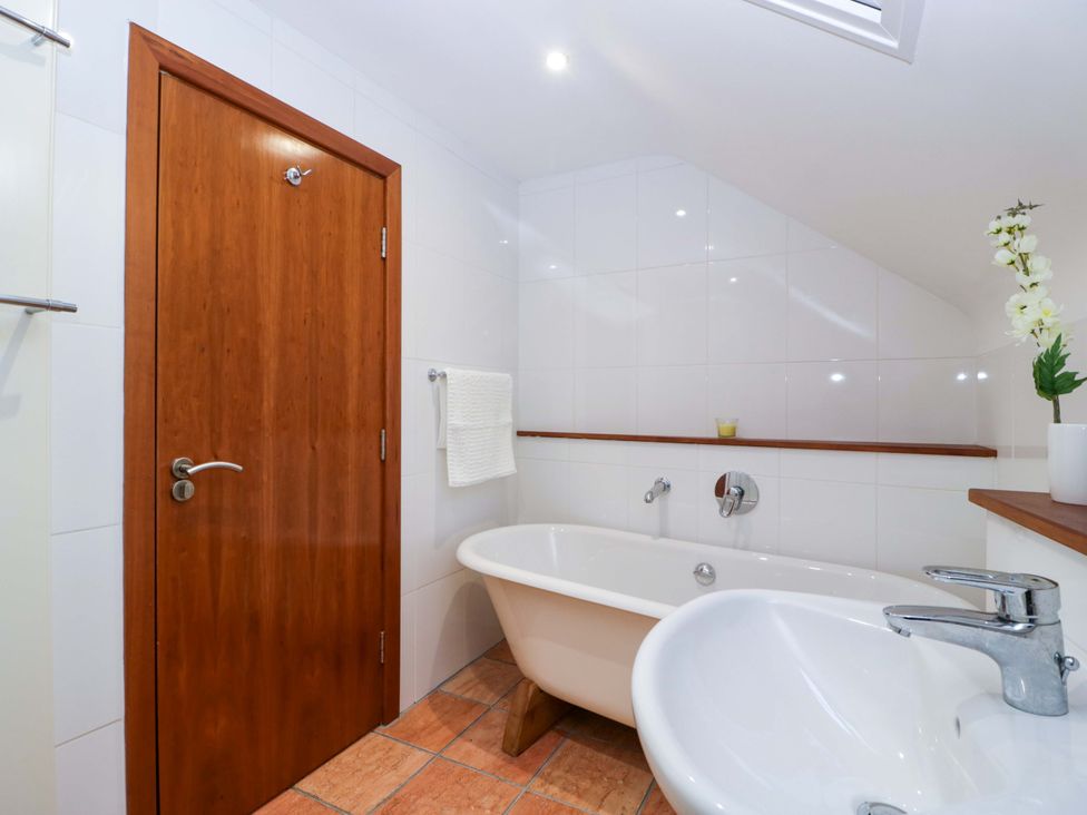 A bathroom with a bath tub and sink at Heathcliffe House in Castleton near Cardiff