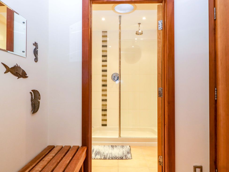 A bathroom with a shower and wooden bench at Heathcliffe House in Castleton near Cardiff