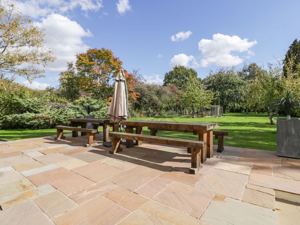 A garden with a wooden table and benches at Heathcliffe House in Castleton near Cardiff