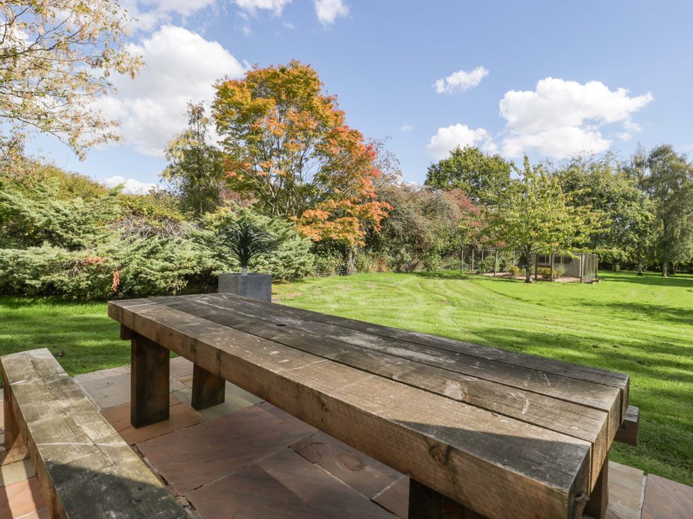 A garden with a wooden table and benches at Heathcliffe House in Castleton near Cardiff
