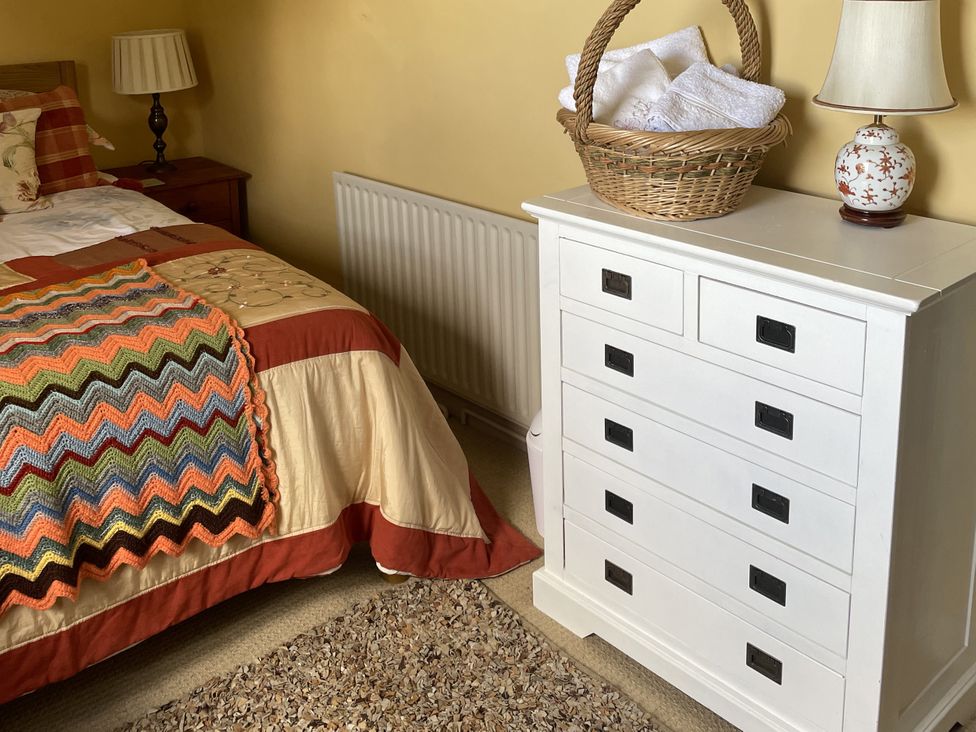 A bedroom with a bed, dresser, lamp and basket at 10 Upper Linney Ludlow
