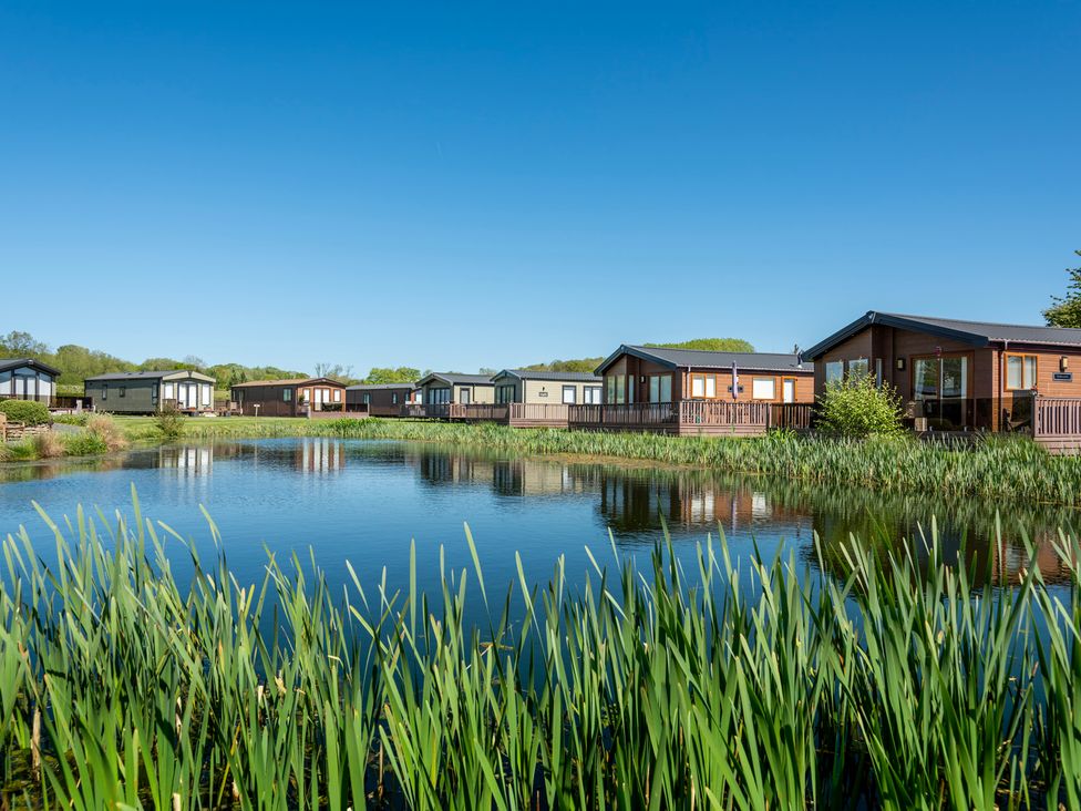 A row of holiday lodges by a pond at Peony in Eardisland