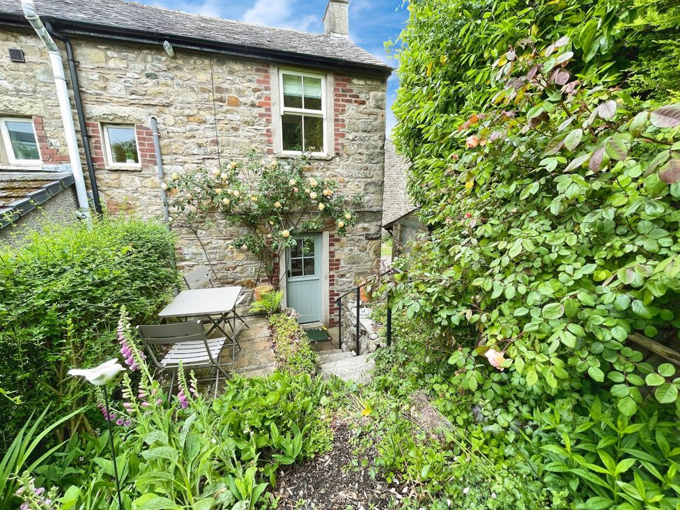 A garden with a stone wall, door, and table with chairs at 3 Chapel Square, Brookhouse near Caton