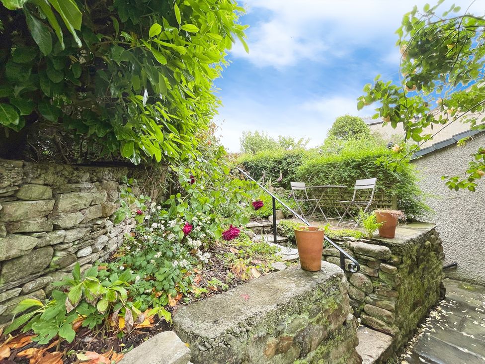 A garden with a stone wall and a dining table with chairs at 3 Chapel Square in Brookhouse near Caton