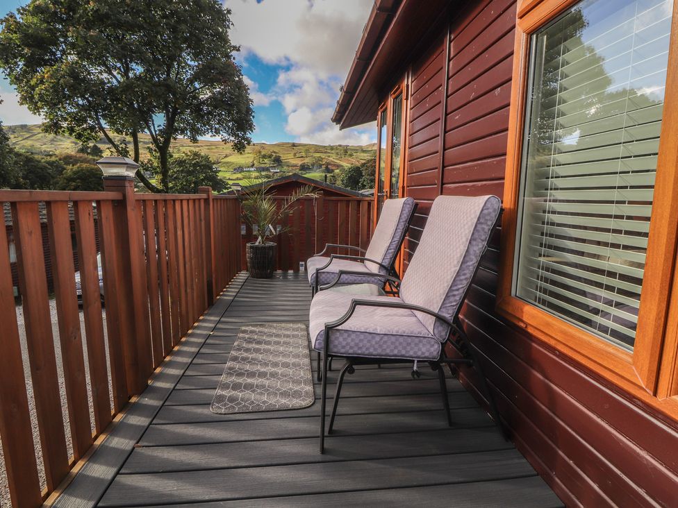 A deck with chairs and a planter at Swifts Reach Lodge near Kirkstone 10, Limefitt Park near Windermere