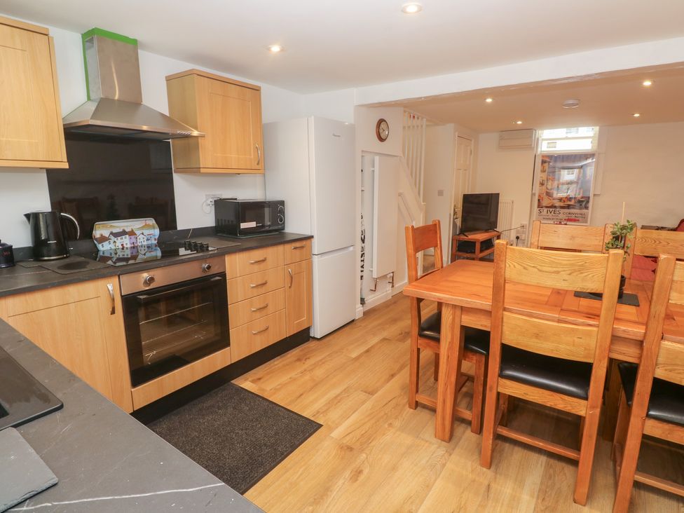 A kitchen with wooden units and dining area at 23 Carncrows Street St Ives