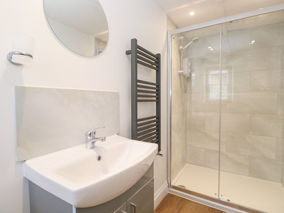 A bathroom with a sink, mirror, and shower at 23 Carncrows Street, St Ives