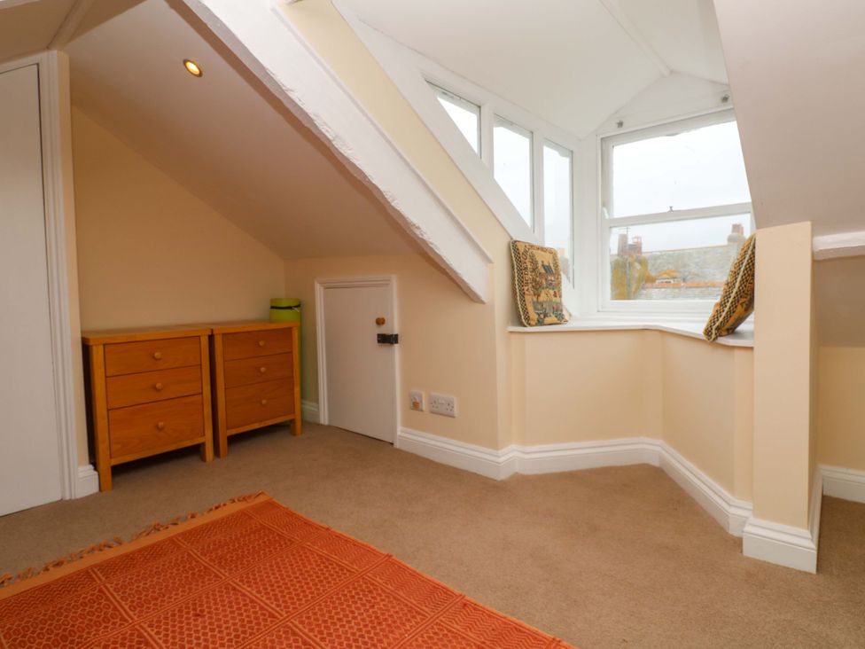 An attic room with a chest of drawers and a window at Rockpools, 23 Carncrows Street St Ives