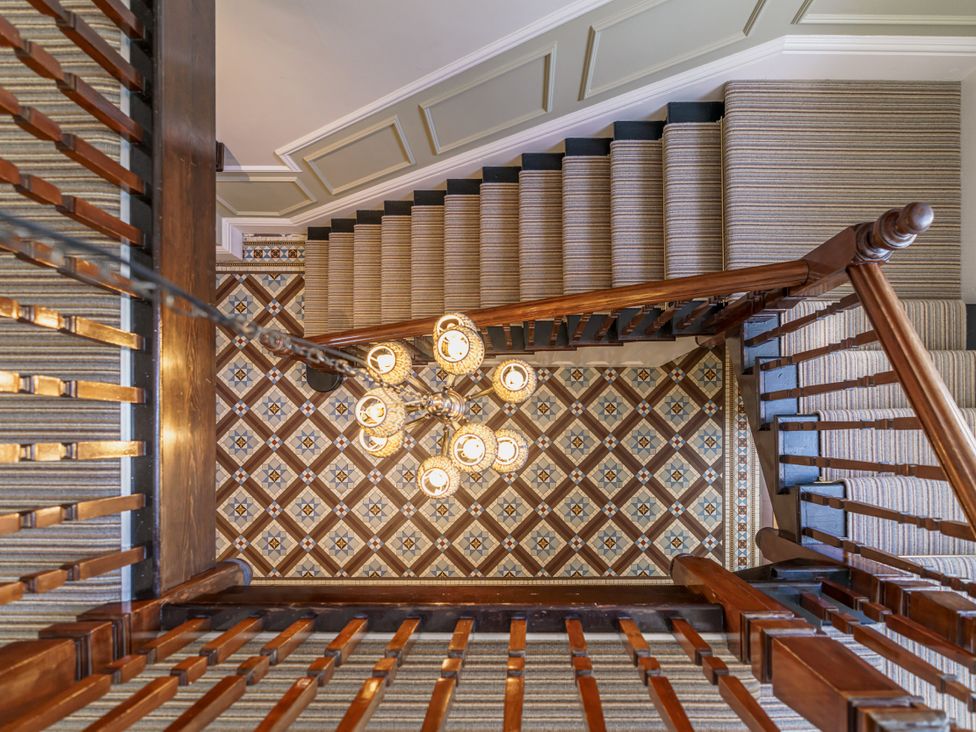 A staircase with a chandelier and patterned floor tiles at Leathes Head Country House Borrowdale near Keswick