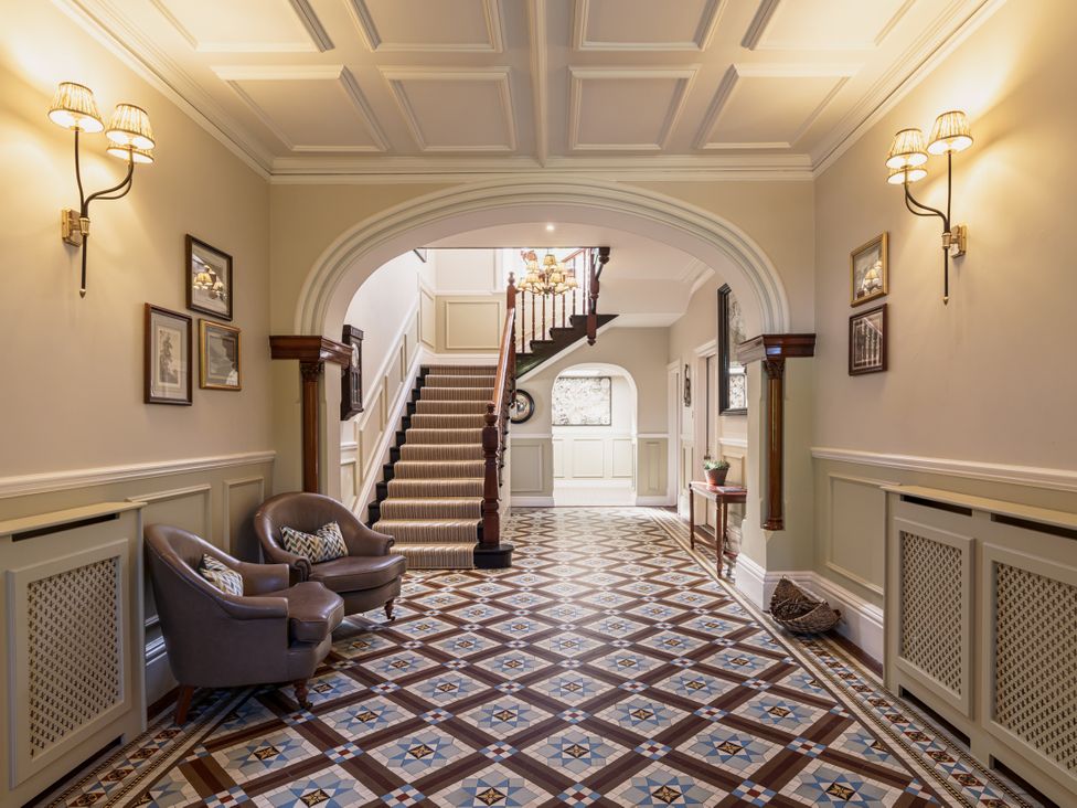 A hallway with stairway and armchair at Leathes Head Country House, Borrowdale near Keswick