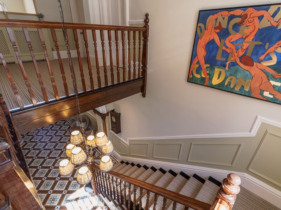 A staircase with a chandelier and painting at Leathes Head Country House in Borrowdale near Keswick