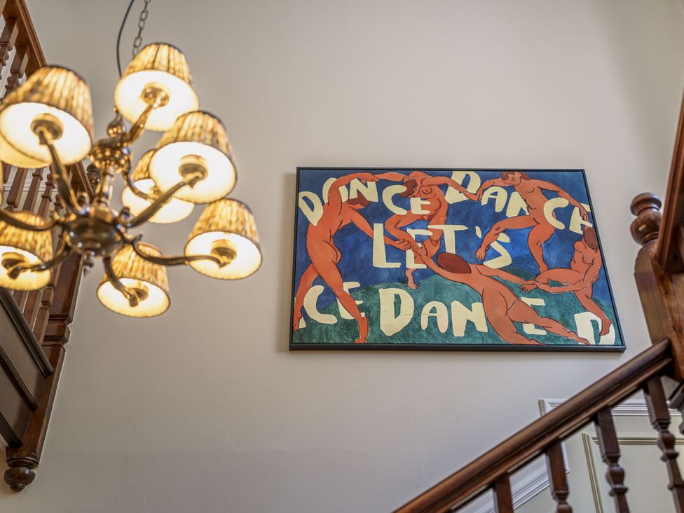 A staircase with a chandelier and wall art at Leathes Head Country House in Borrowdale near Keswick