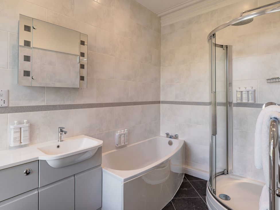 A bathroom with a bathtub, shower, mirror, and sink at Leathes Head Country House in Borrowdale near Keswick