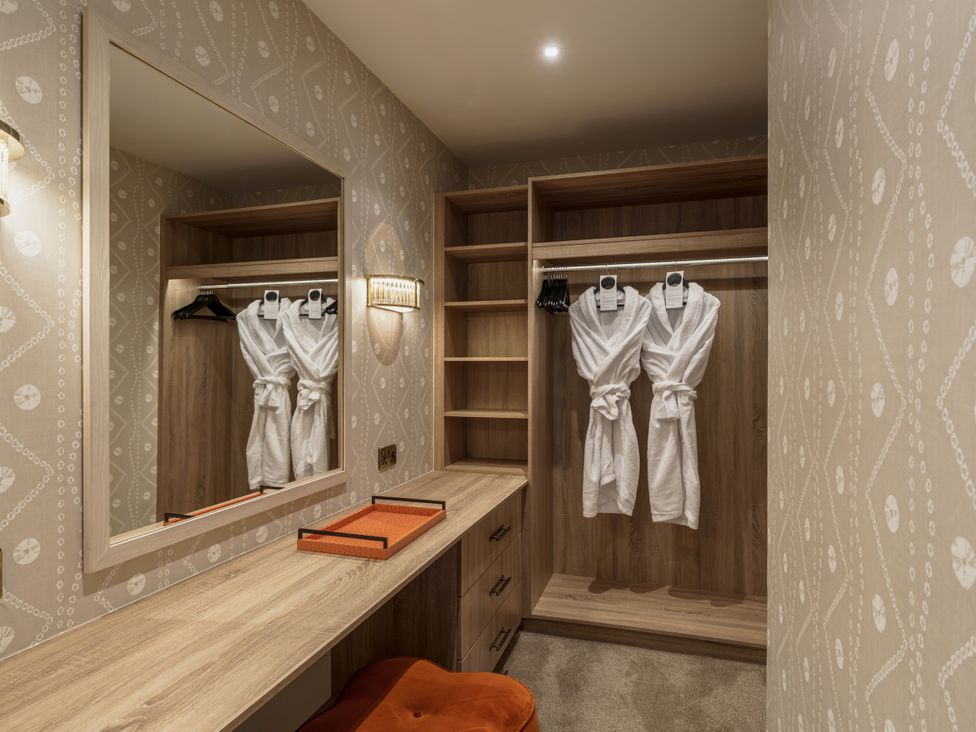 A dressing room with robes hanging and a mirror at Leathes Head Country House Borrowdale near Keswick