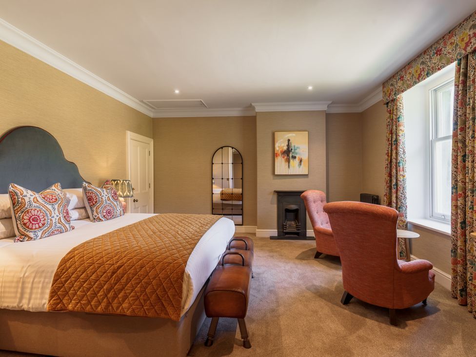 A bedroom with a bed and armchairs at Leathes Head Country House in Borrowdale near Keswick