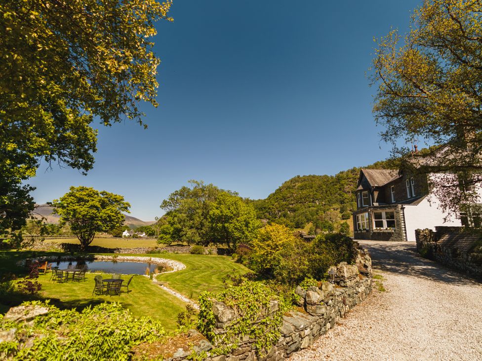 An outdoor view of a house with a pond and seating area at Leathes Head Country House Borrowdale near Keswick