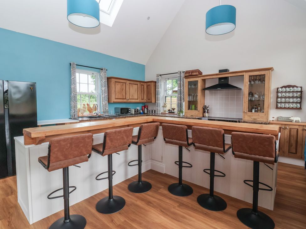 A kitchen with bar stools and cabinets at Crossett Grange in Driffield