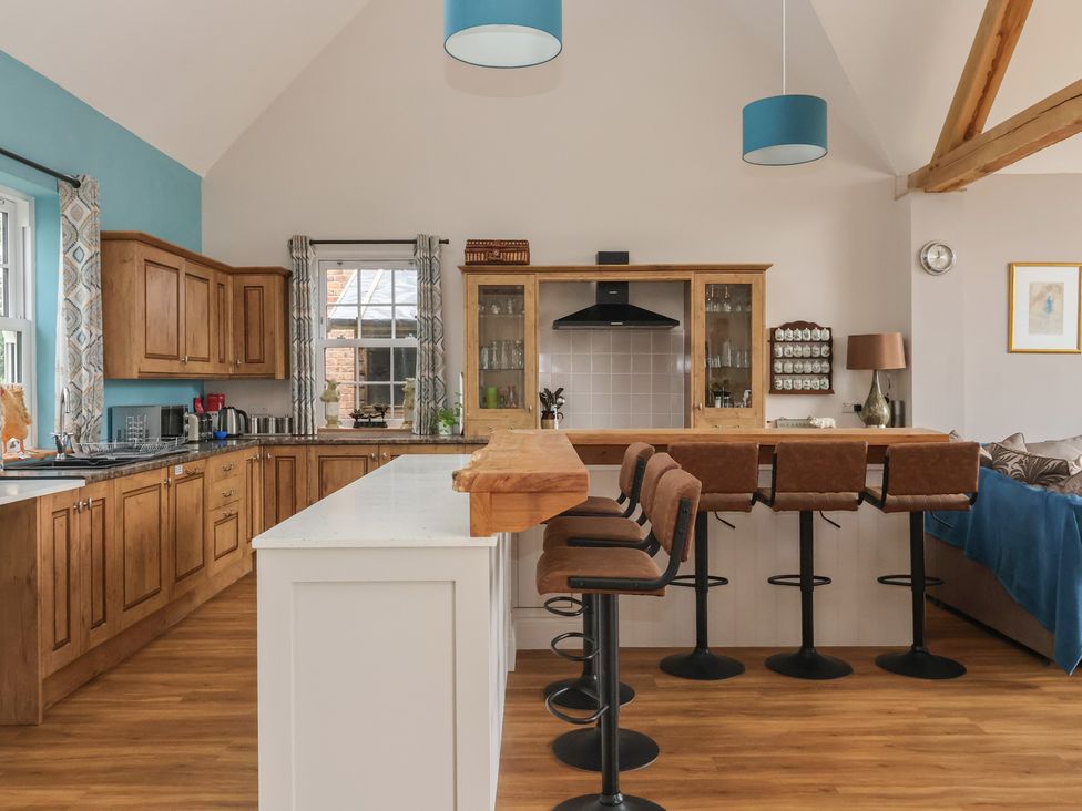 A kitchen with wooden cabinetry and bar stools at Crossett Grange in Driffield