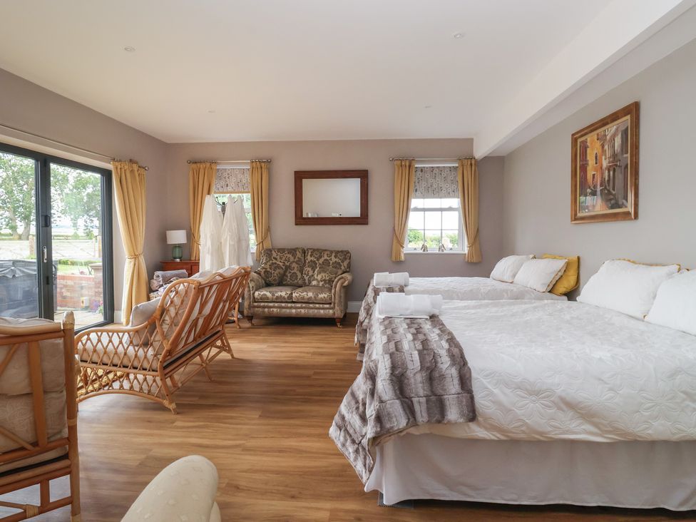 A bedroom with two beds and a seating area at Crossett Grange in Driffield
