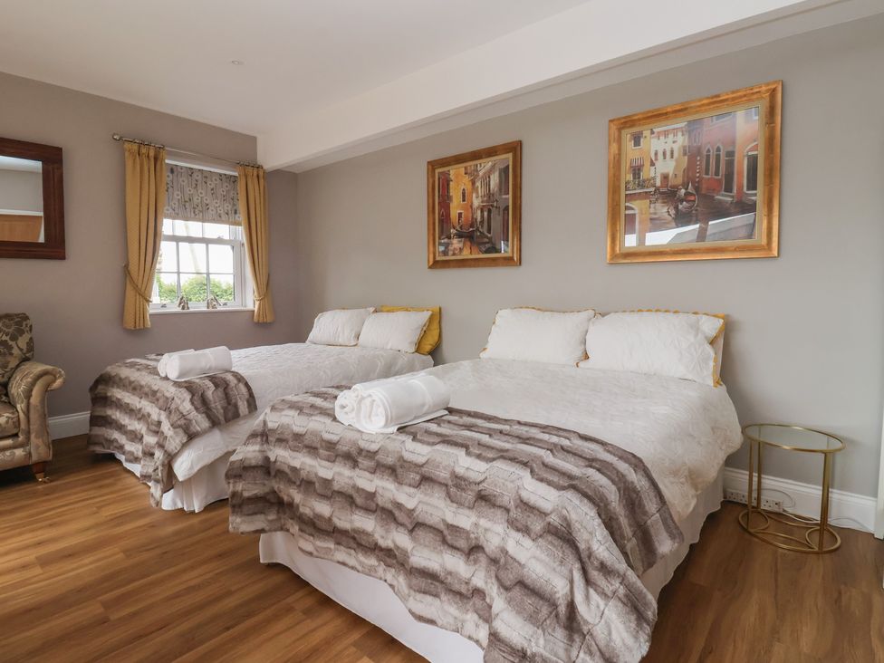 A bedroom with two beds and an armchair at Crossett Grange in Driffield