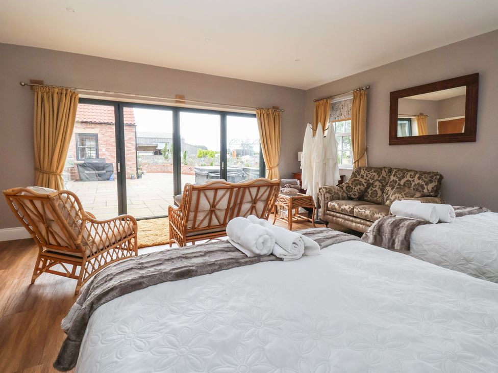 A bedroom with two beds and a sliding glass door at Crossett Grange Driffield