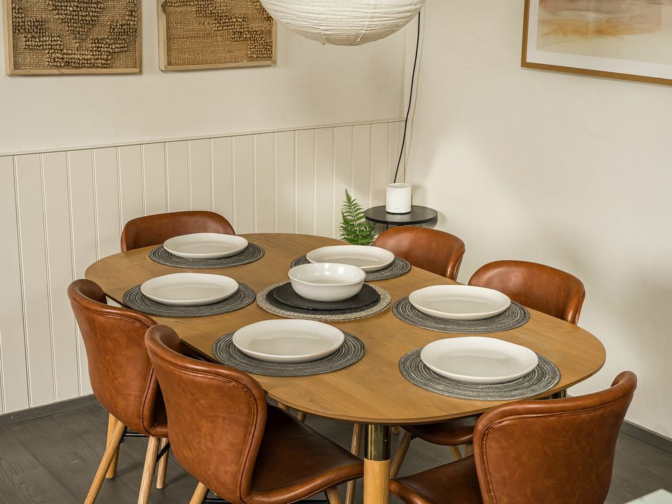 A dining table set with plates and chairs at Grove Cottage in Kington