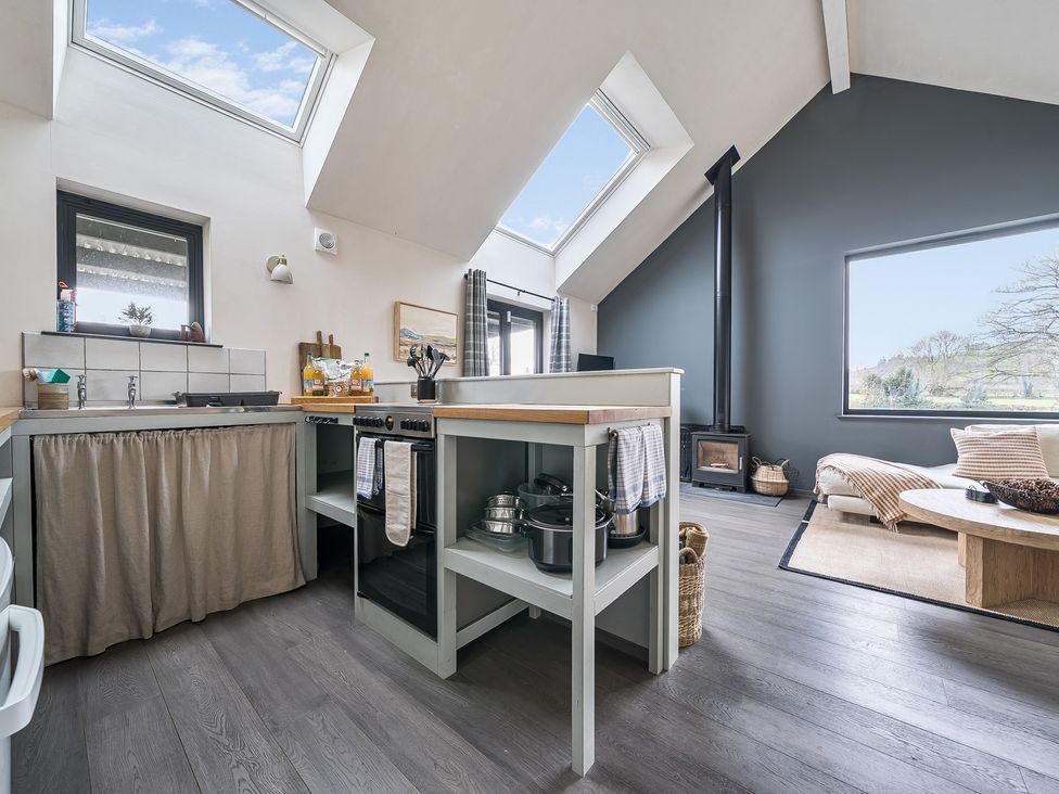 A kitchen with windows, sink, stove, and a dining table at Grove Cottage in Kington