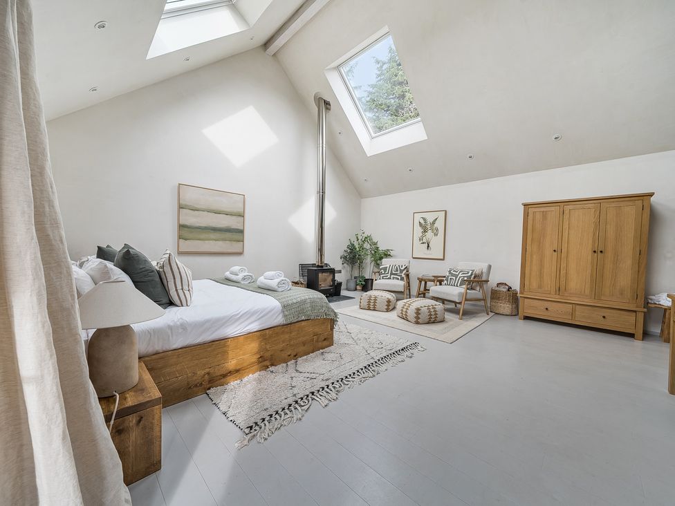 A bedroom with a wooden bed and chairs at Grove Cottage in Kington