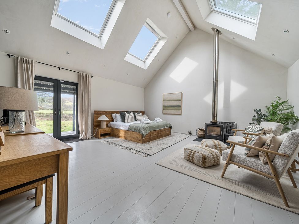 A bedroom with a bed, sofa, and stove at Grove Cottage in Kington