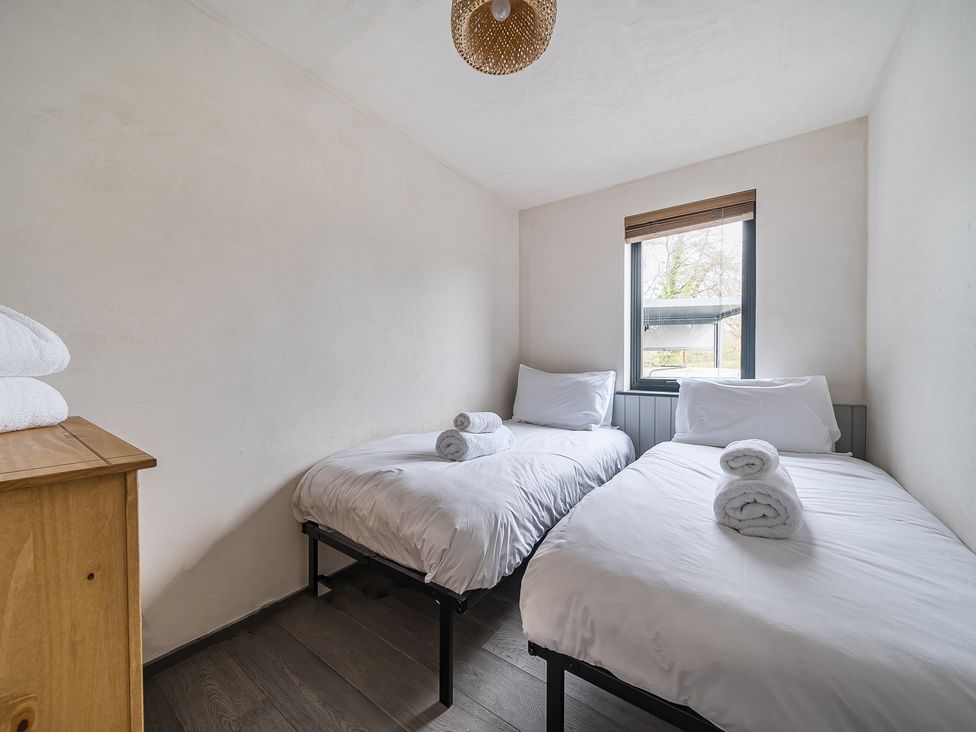 A bedroom with two beds and towels on a dresser at Grove Cottage in Kington
