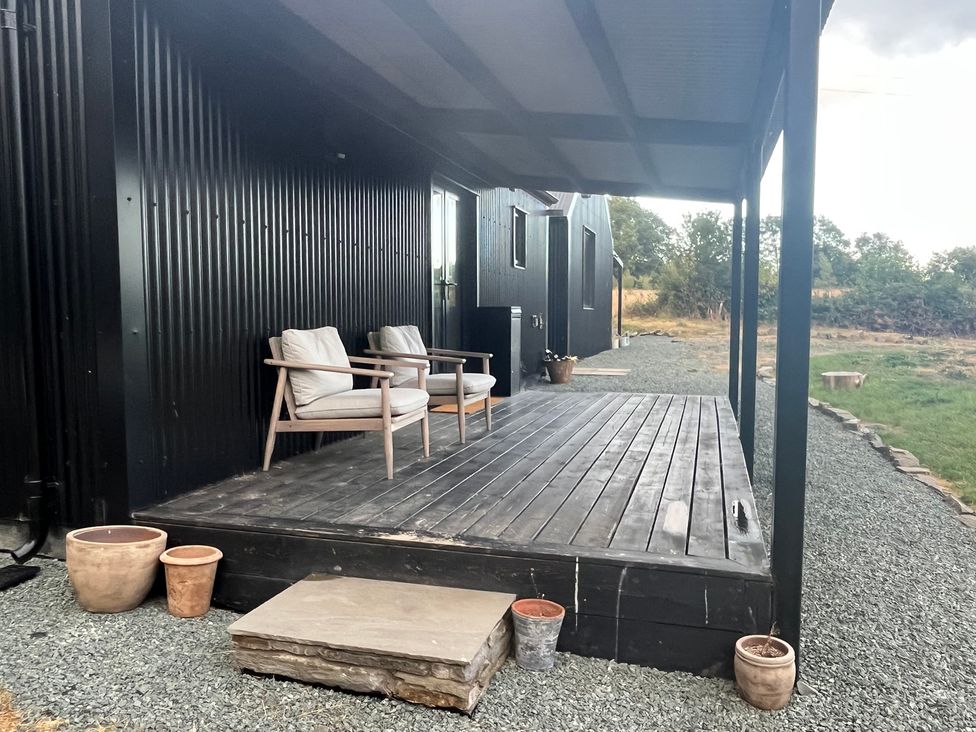 A deck with chairs and potted plants at Grove Cottage in Gladestry