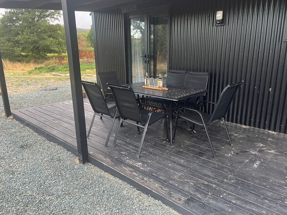 An outdoor seating area with a table and chairs at Grove Cottage Gladestry