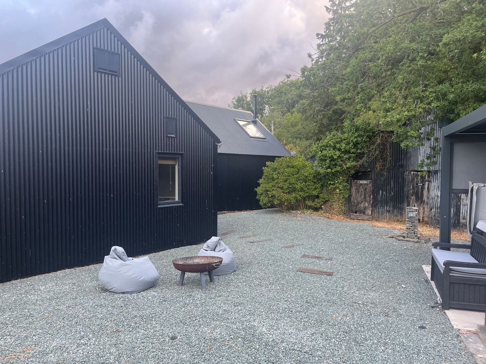 An outdoor area with black houses, bean bags, and a fire pit at Grove Cottage in Gladestry