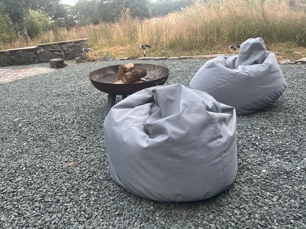 A fire pit with logs and two bean bags at Grove Cottage in Gladestry