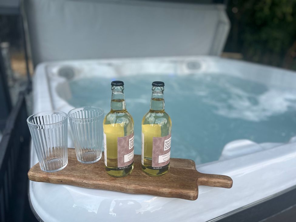 A hot tub with drinks and glasses at Grove Cottage in Gladestry