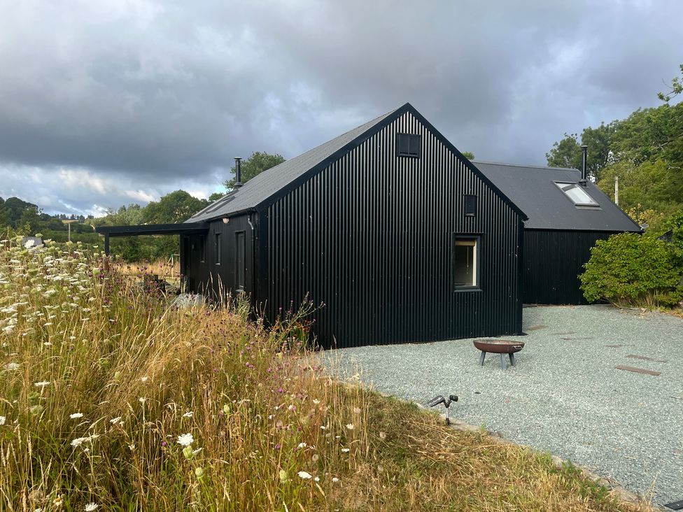 A black house with a gravel area in front at Grove Cottage in Gladestry