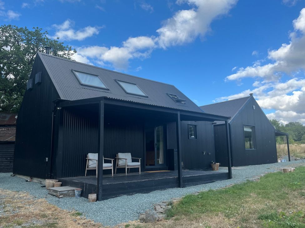A house with a deck and chairs at Grove Cottage in Gladestry