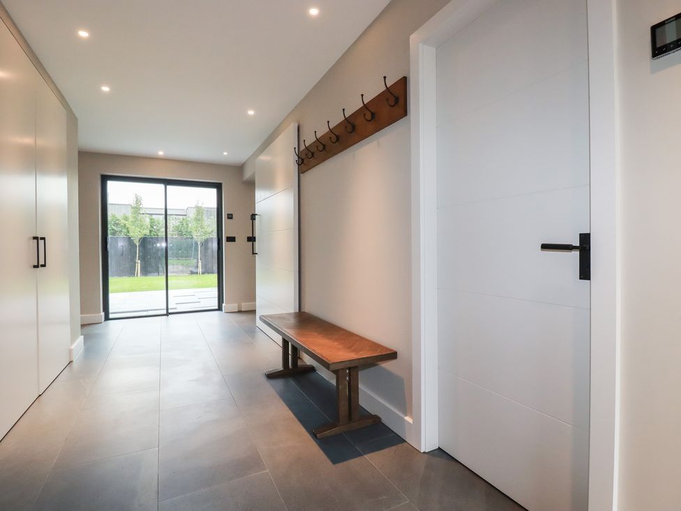 A hallway with a bench and sliding glass door at Harberton