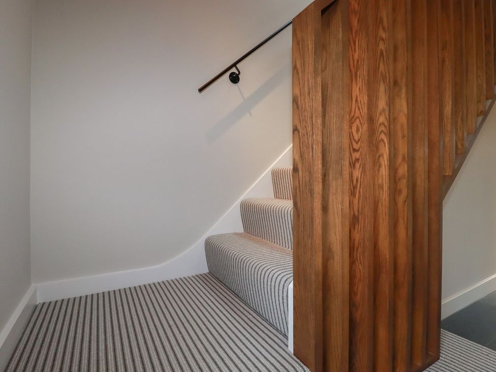 A staircase with wooden handrail and carpeted steps at Harberton