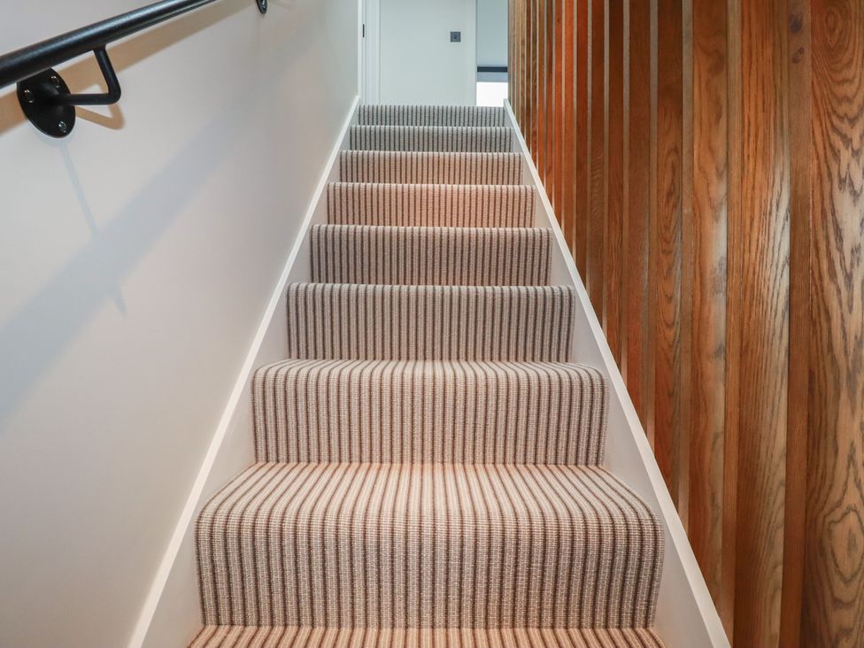 A staircase with striped carpet and a wooden handrail at Harberton