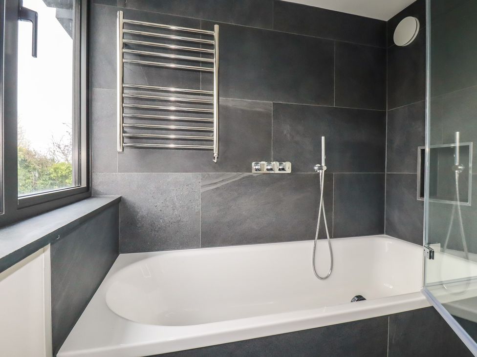 A bathroom featuring a bathtub, towel rail, and shower at Harberton