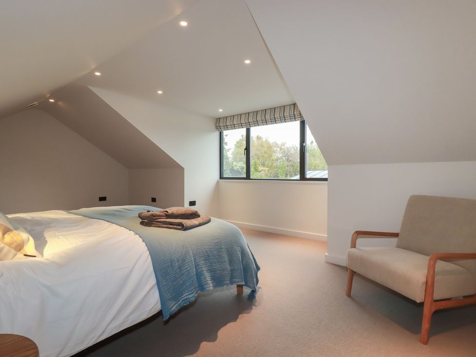 A bedroom with a bed and armchair at Harberton 