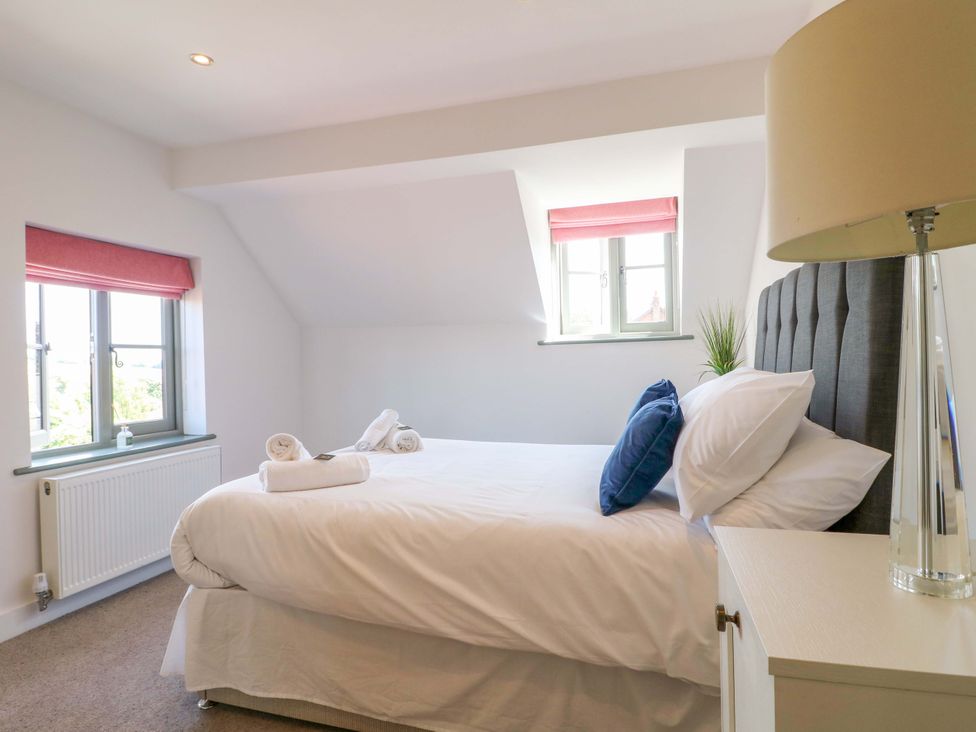 A bedroom with a bed and windows at New Elms Farmhouse in Melbourne, Derbyshire