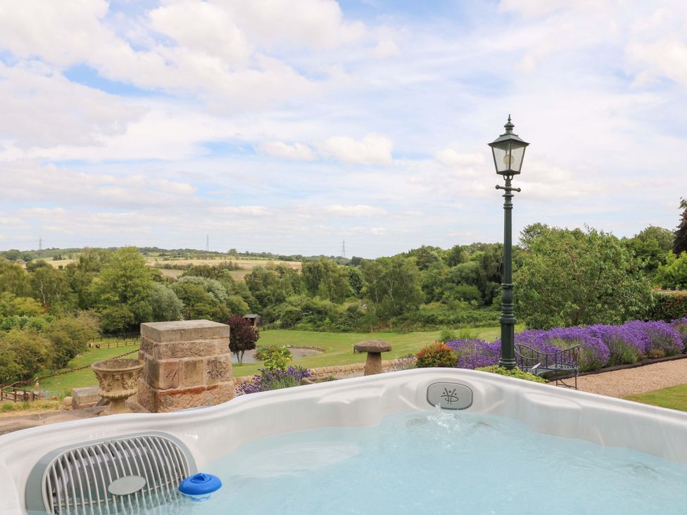 An outdoor area with a hot tub and a view of the landscape at New Elms Farmhouse in Melbourne, Derbyshire