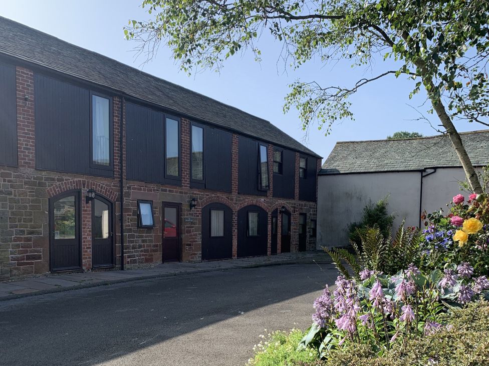 An outdoor area with a building and flowers at Millers Cottage in Seaville near Wigton