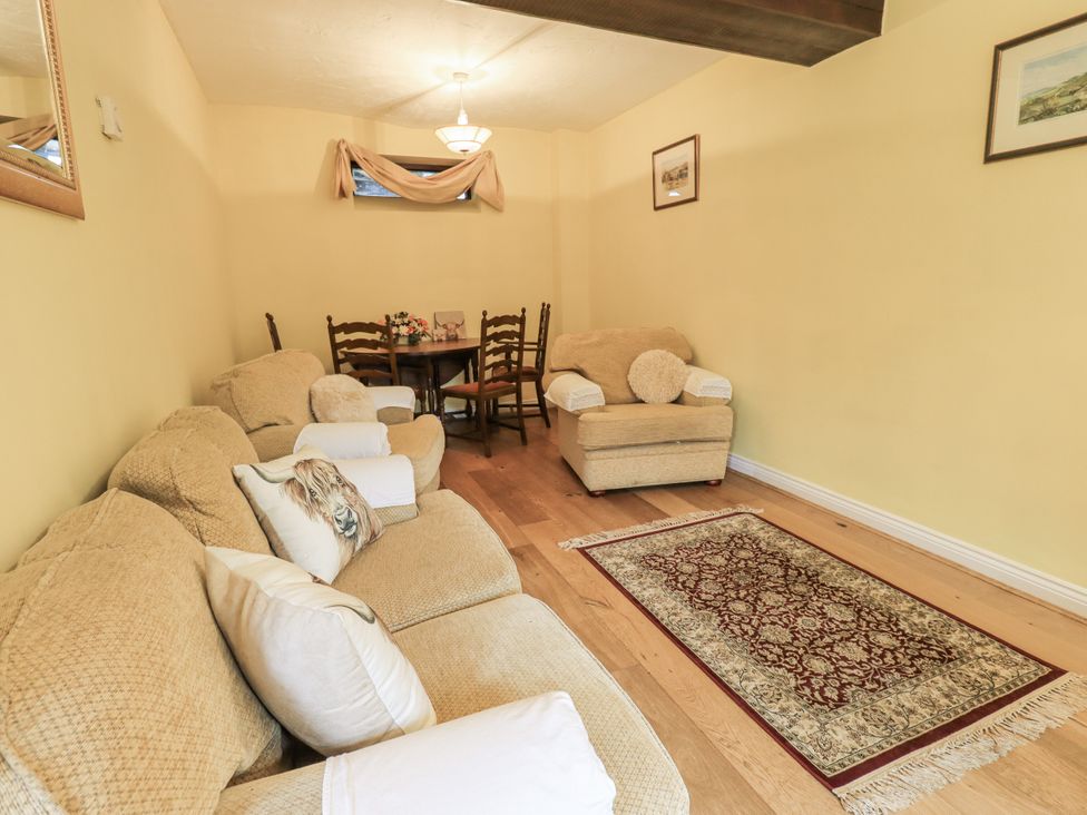 A living room with a sofa and dining table at Millers Cottage in Seaville near Wigton