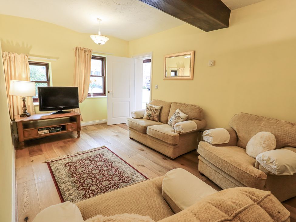 A living room with a sofa and television at Millers Cottage in Seaville near Wigton