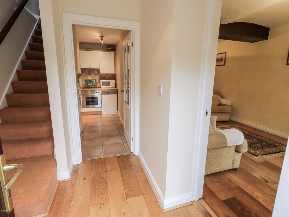 A hallway with stairs leading to the kitchen at Millers Cottage in Seaville near Wigton