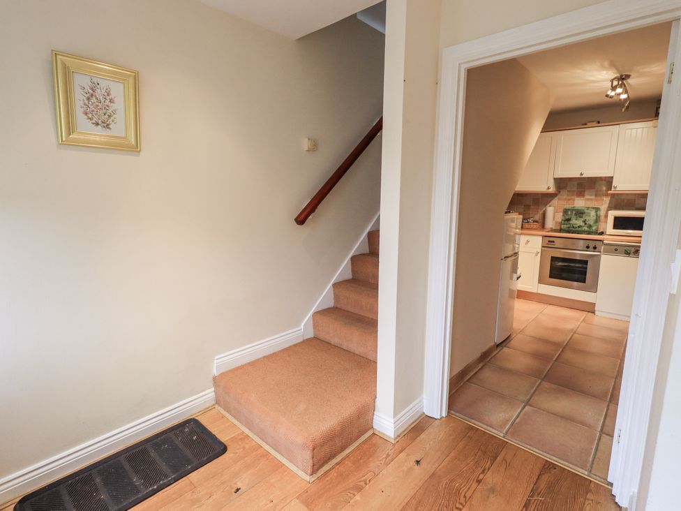 A hallway with a staircase and a view into the kitchen at Millers Cottage Seaville near Wigton